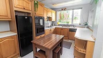 A kitchen with wooden cabinets, a black refrigerator, a stove, and a sink.
