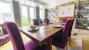 A dining area with a wooden table, purple upholstered chairs, and a wall with a collage of photographs.