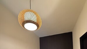 Un couloir avec un escalier, un mur à texture et un luminaire suspendu.