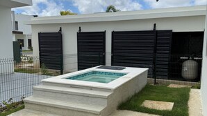 Un espace piscine extérieur moderne, doté d’une terrasse en béton, d’une petite pelouse et d’une clôture en métal.