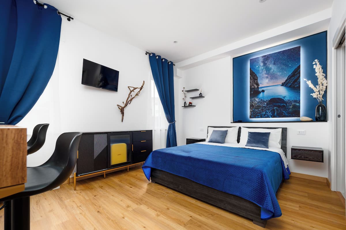 A modern bedroom with a bed, a TV, a desk, and a chair.