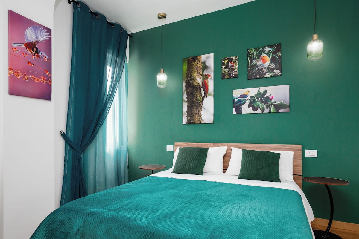 A room with a bed, a round table, and artwork on the walls.