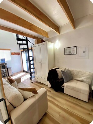 A living room with a white sofa, a white cabinet, and a wooden ceiling.