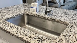 Eine Küche mit Granitabdeckung, Spüle aus Edelstahl und einer Seifenspender.