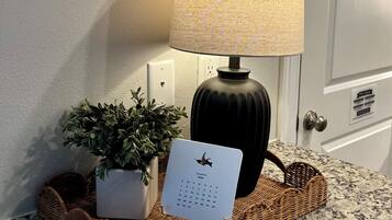 Een lamp, een potplant en een kalender op een geweven dienblad op een granieten aanrecht.
