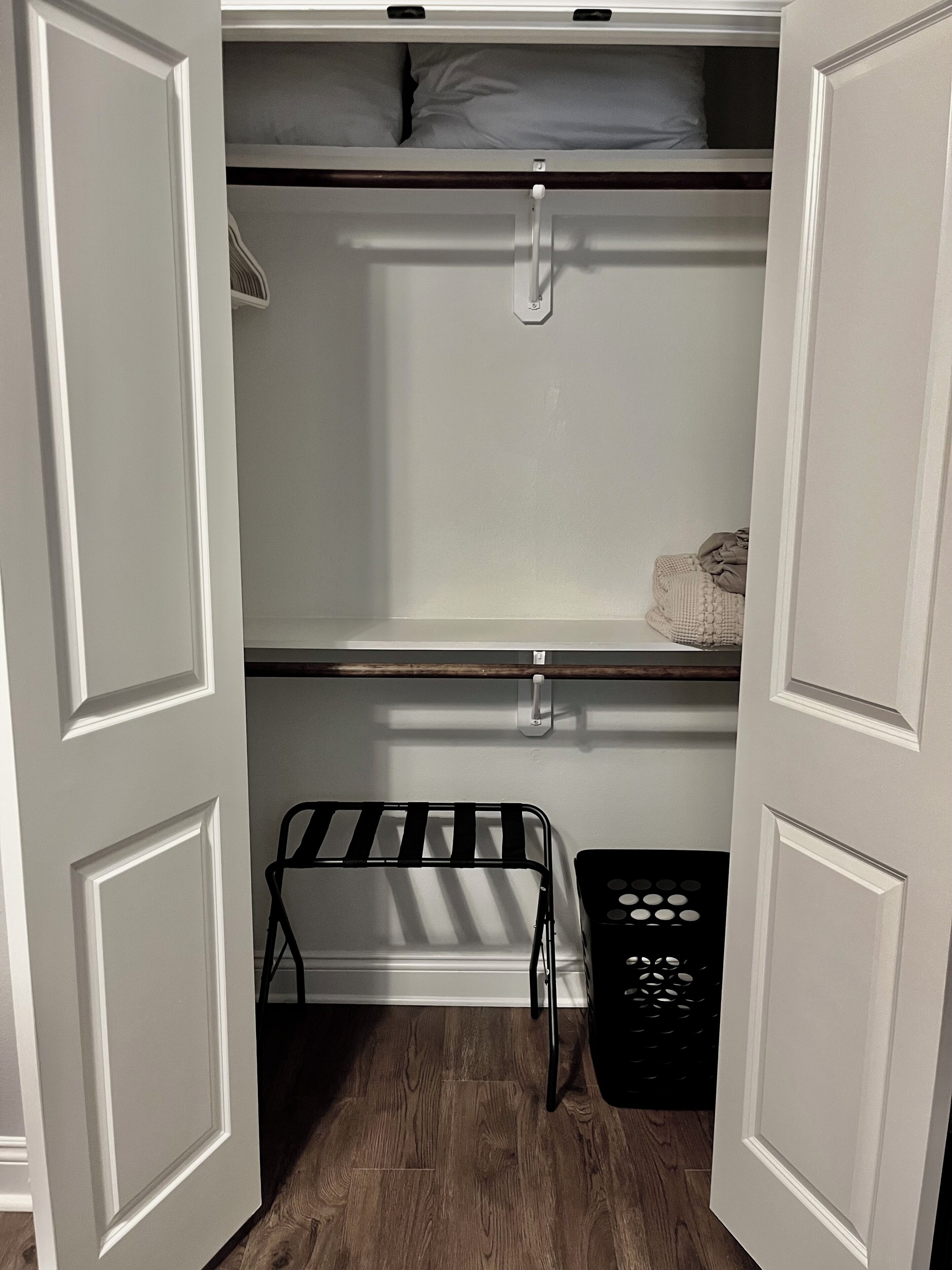A closet with open doors, shelves, and a hanging rack.
