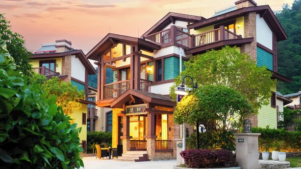 A multi-story hotel with a balcony, a sign with Chinese characters, and a well-maintained garden. - Pandora Valley Villas (Zhangjiajie)