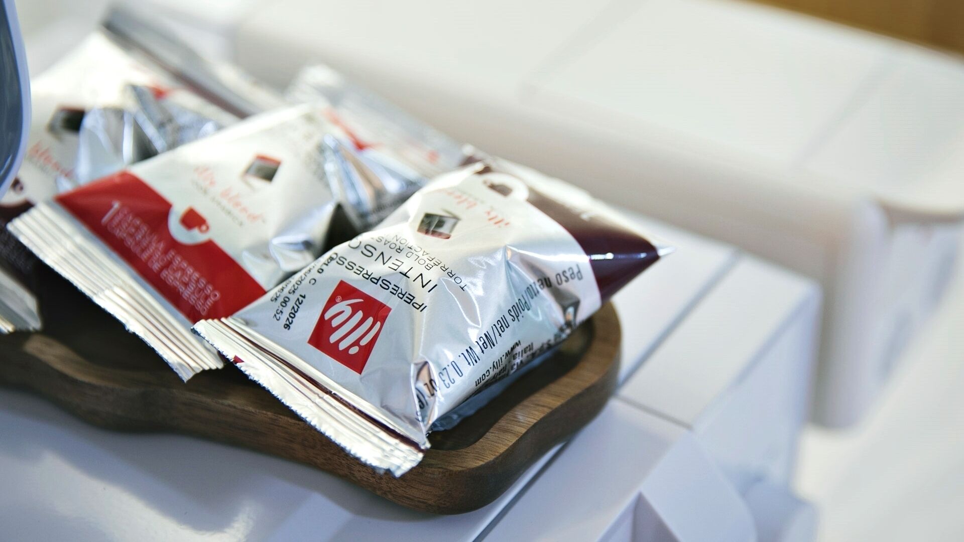 A tray with several packets of instant coffee on a wooden surface.