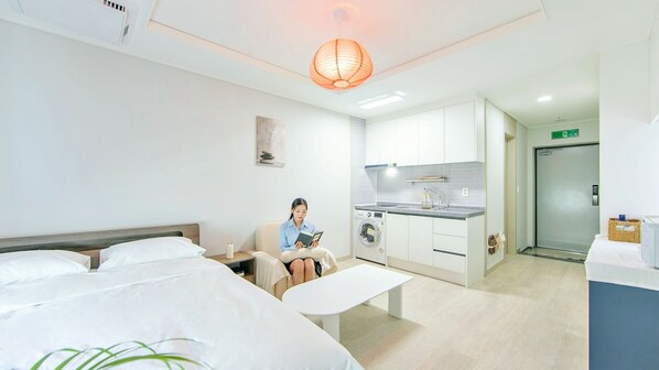 A hotel room with a bed, a reading chair, a desk, a washing machine, and a kitchenette. - Busan Ieumjae Seomyeon Station (Busan)
