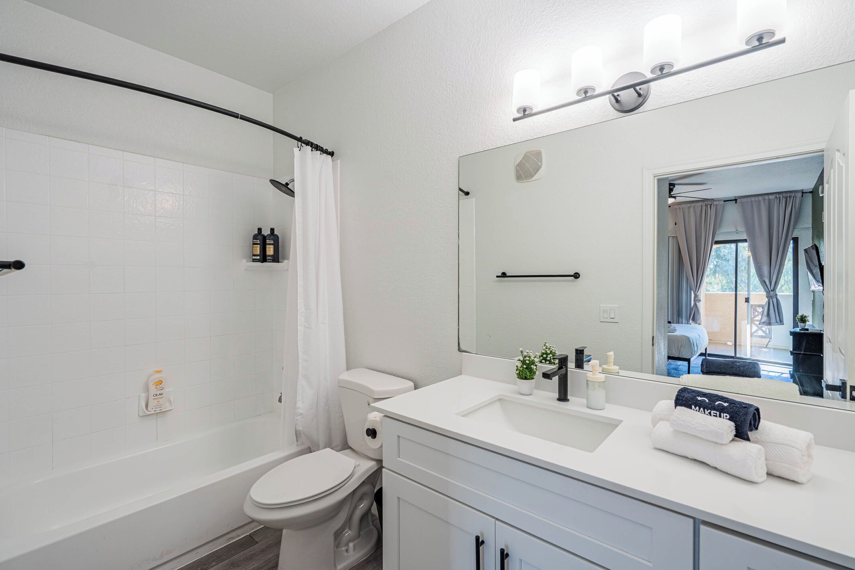 Et moderne badeværelse med badekar, toilet og vaskebord med spejl.