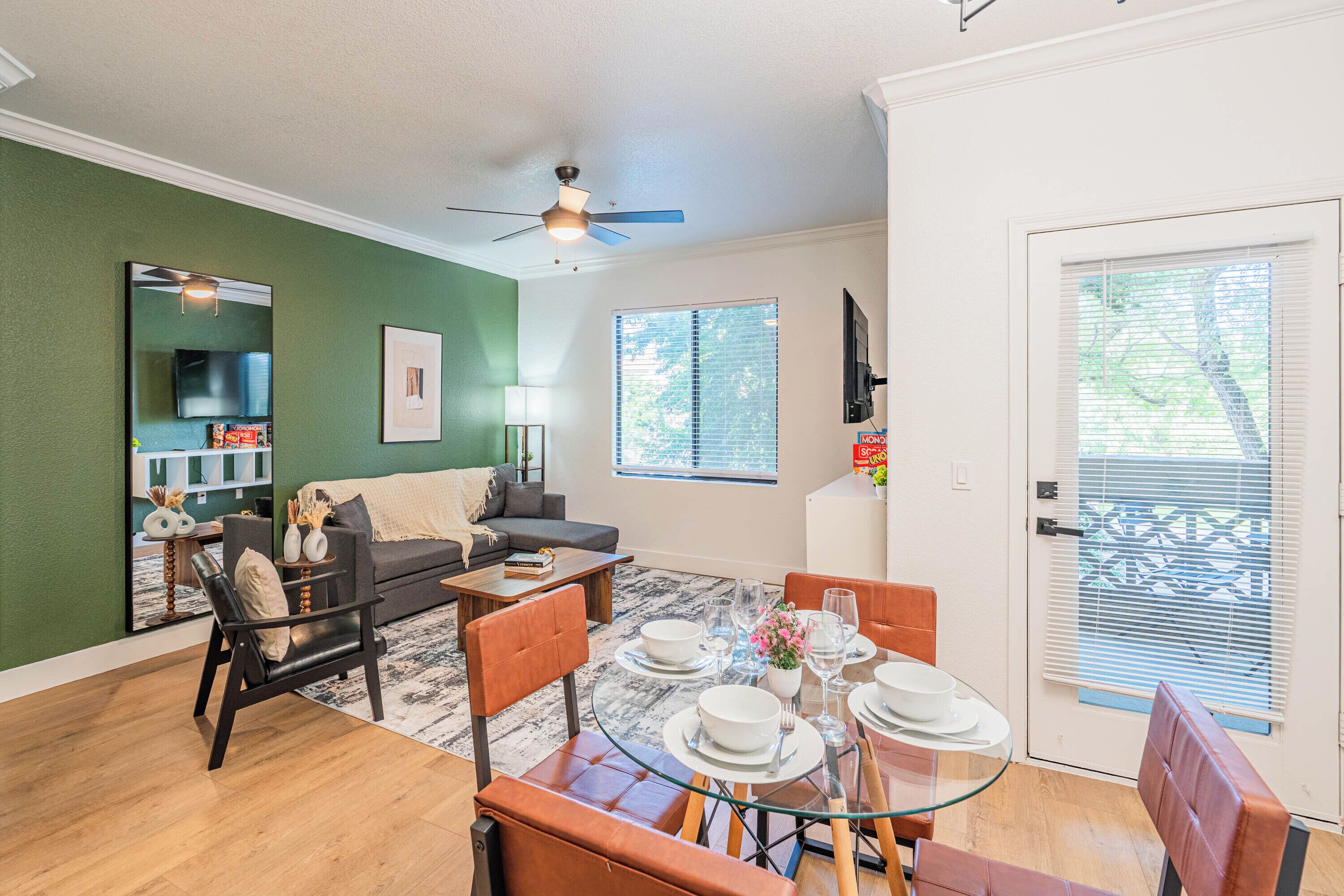 A living room with a sofa, coffee table, and dining table set for four.