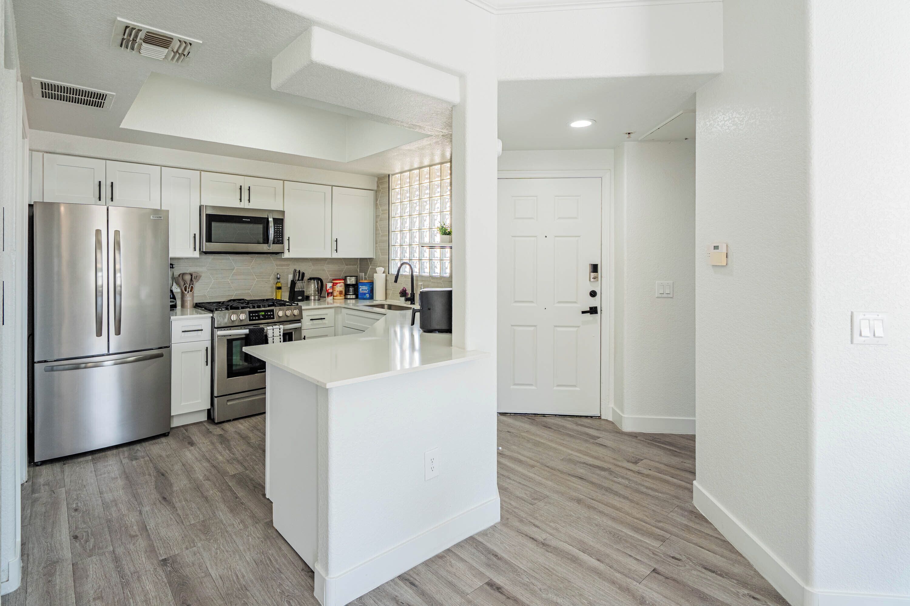 A modern kitchen with stainless steel appliances, white cabinetry, and a central island.