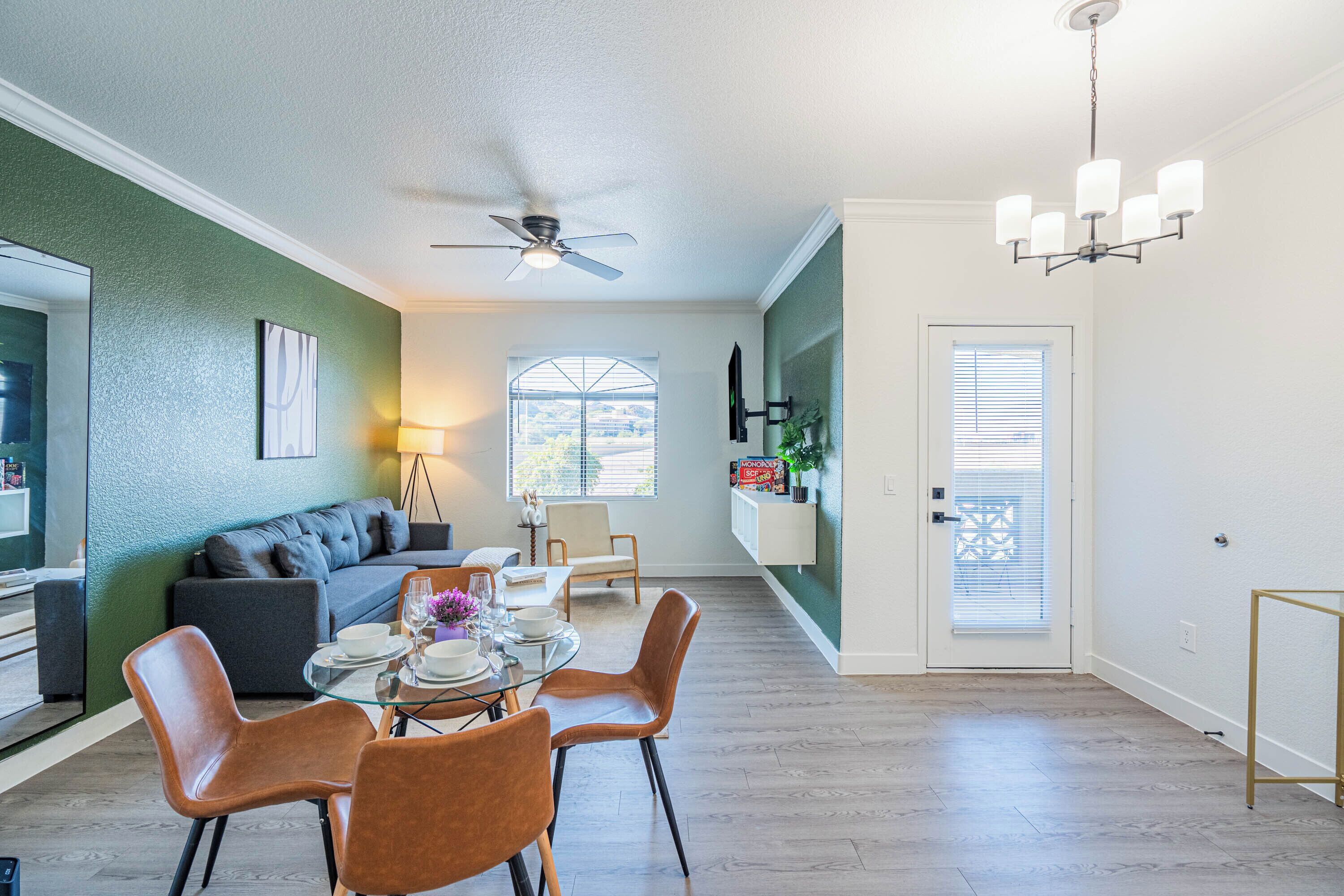 A dining area with a table set for four, a sofa, and a ceiling fan.