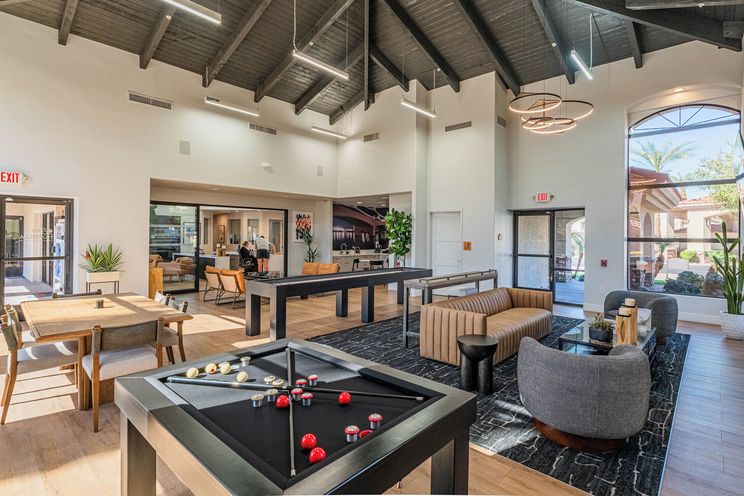 A spacious lobby with a pool table, seating areas, and a view of the outside.