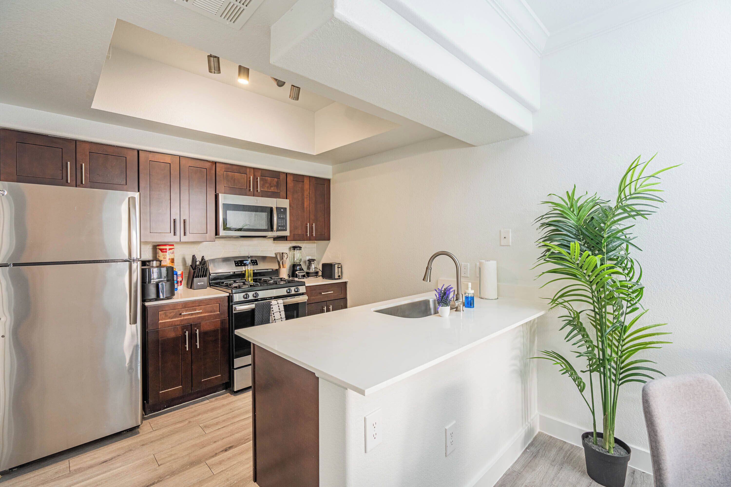 A modern kitchen with stainless steel appliances, wooden cabinets, and a central island.