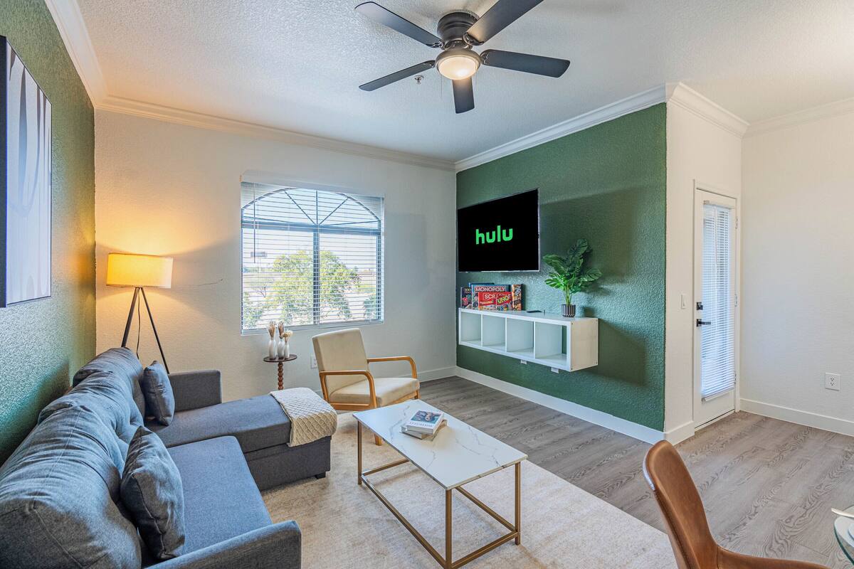 Un salon comprenant un canapé, un fauteuil, une table basse, un téléviseur et un ventilateur de plafond.