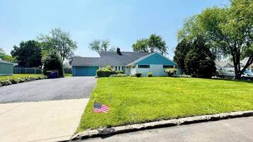 A residential street with a house, a well-maintained lawn, and a flag.