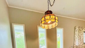 Une pièce comprenant un banc en bois servant de coin salon, une table et un luminaire suspendu.
