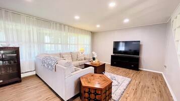 A modern living room with a sofa, a coffee table, a TV, and a bookshelf.