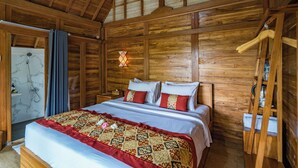 Une chambre à coucher aux murs lambrés, avec un lit, des tables de chevet, un luminaire suspendu et une étagère en bois.