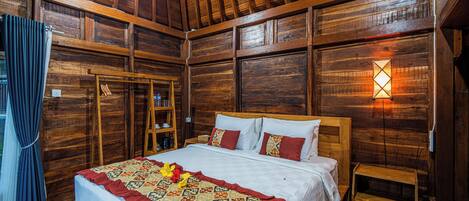 A wooden room with a bed, a nightstand, and a wall-mounted light fixture.