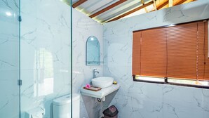 Une salle de bain avec un mur en marbre blanc, un lavabo blanc, un miroir et une fenêtre avec des stores.