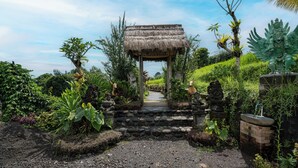 Un sentier mène à une construction à toit de chaume, sur laquelle est apposée une pancarte indiquant les activités proposées dans le cadre d’un tourisme écologique.