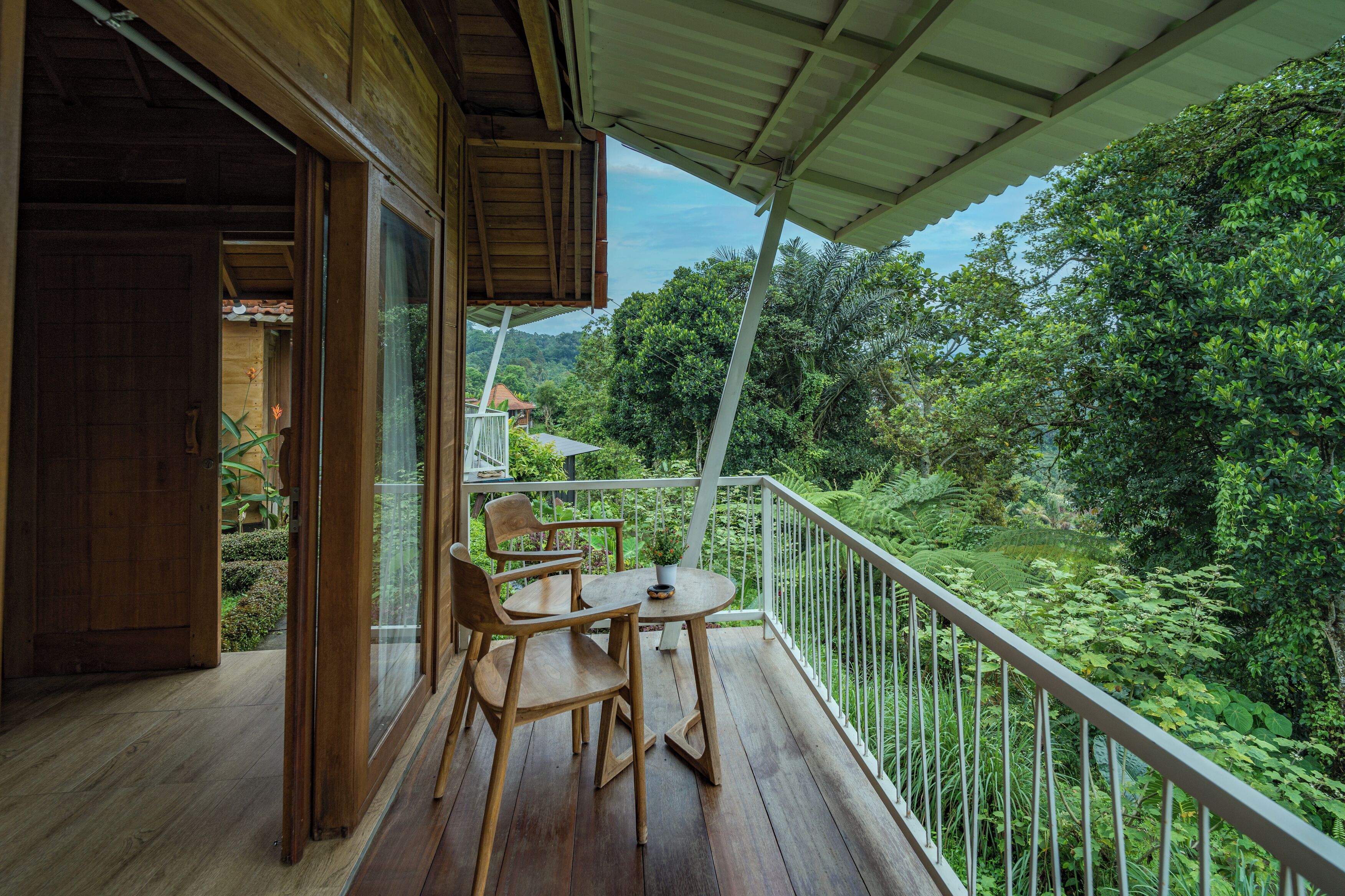 A wooden deck with a table and chairs, overlooking a lush green landscape.