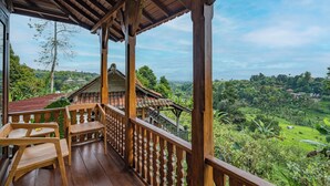 Un balcon en bois offrant une vue sur un paysage verdoyant et luxuriant.