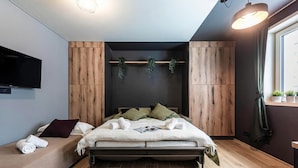 Un dormitorio moderno con una cama, una mesita de noche, un televisor y una ventana.
