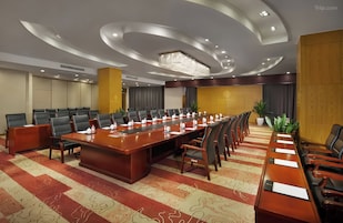 Uma sala de conferências com uma mesa comprida, cadeiras e piso coberto de carpete.