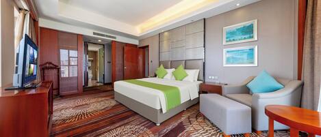 Ein Hotelzimmer mit Bett, Sofa, Fernseher und Schreibtisch.