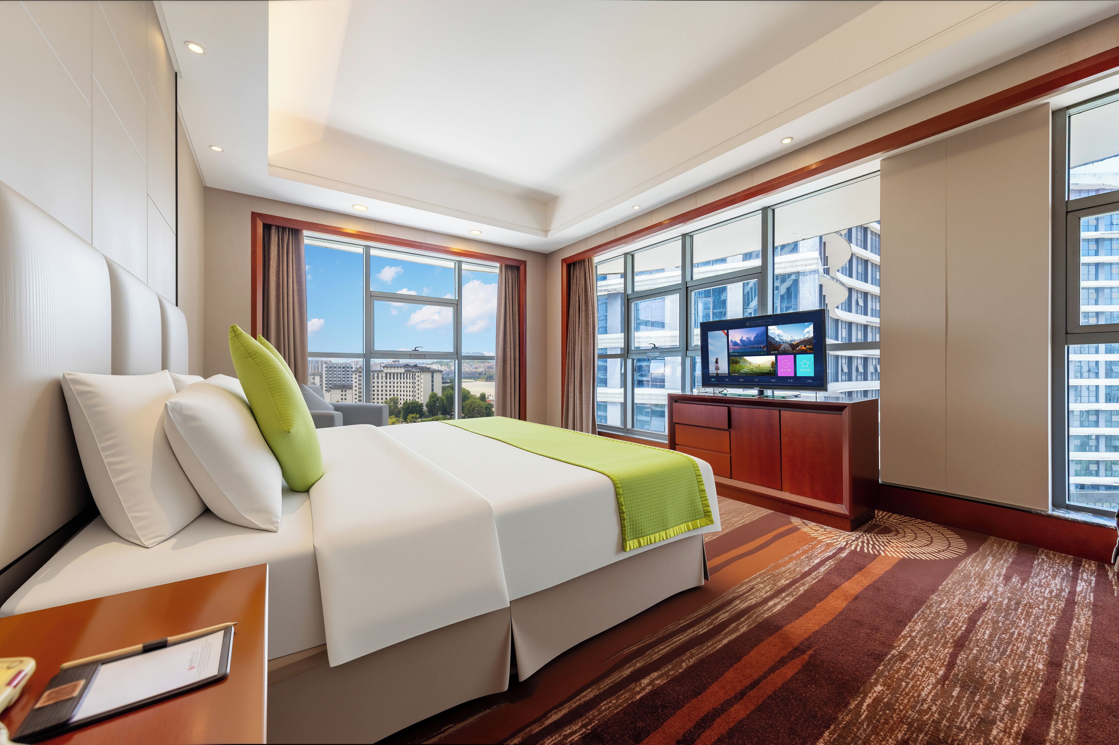 A hotel room with a bed, a TV, a desk, and a large window with a city view.