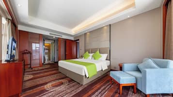 A hotel room with a large bed, a seating area, and a television.