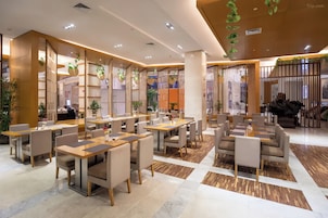 A modern restaurant with multiple dining areas, wooden tables, and chairs.