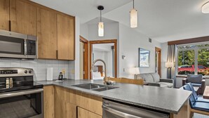 Una cocina moderna con electrodomésticos de acero inoxidable, armarios de madera, lavavajillas integrado y un amplio ventanal con vistas al exterior.