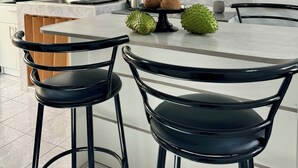 Une cuisine moderne avec un îlot central, des tabourets de bar, une machine à café et une petite plante en pot.