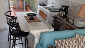 Une cuisine compacte avec un coin repas, un canapé et une porte-fenêtre coulissante donnant sur une terrasse extérieure.