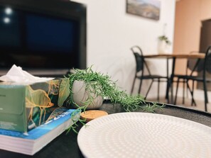 Un comedor con una mesa, sillas, un televisor y una planta.