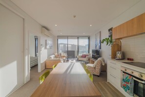 A modern kitchen with a dining area, a sofa set, and a large window. - Modern Central City Sanctuary on Welles Street (Christchurch)