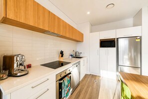 Eine moderne Küche mit weißen Schränken, einem Edelstahl-Kühlschrank und einem eingebauten Ofen.