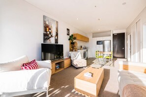 Ein modernes Wohnzimmer mit Flachbildfernseher, einer Couch, einem Couchtisch und einem Essbereich mit Stühlen.