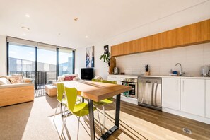 A modern apartment with a dining area, kitchen, and a balcony with a city view. - Welles St | Christchurch CBD | Sleeps 4 | Balcony (Christchurch)