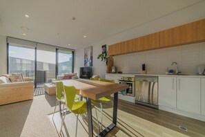 A modern kitchen with a dining area, wooden cabinets, and a large window. - Modern Central City Sanctuary on Welles Street (Christchurch)