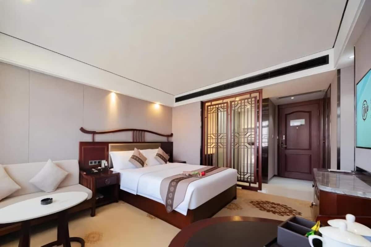 Una habitación de hotel con cama, mesita de noche, silla y una pequeña mesa.