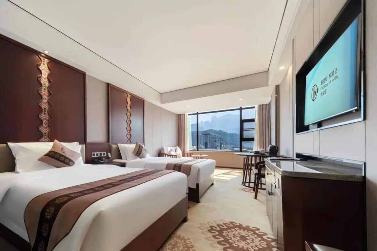 Habitación de hotel con dos camas, televisión, escritorio y vistas a las montañas.