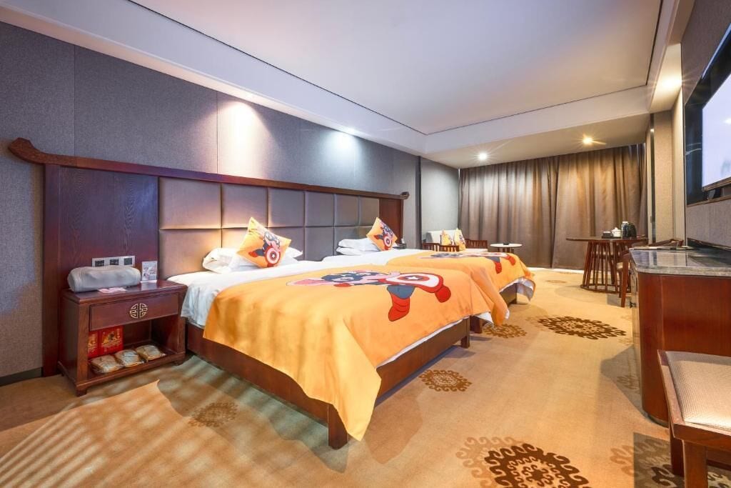 Habitación de hotel con dos camas, un escritorio, una silla, un televisor y un minibar.