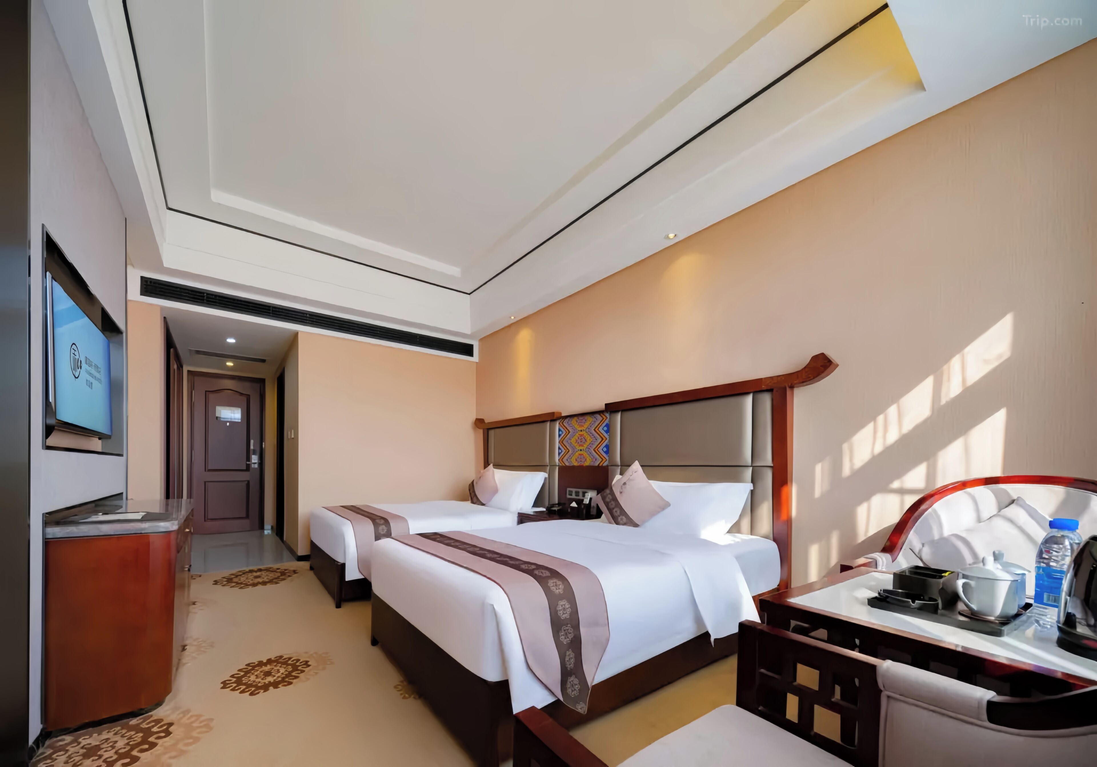 Habitación de hotel con dos camas, un escritorio, televisor y puerta al baño.