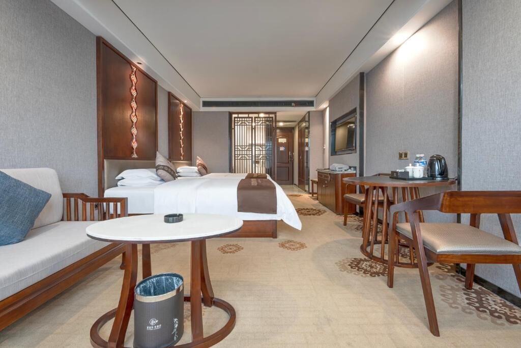 A hotel room with a bed, a sofa, a dining table, and a desk.
