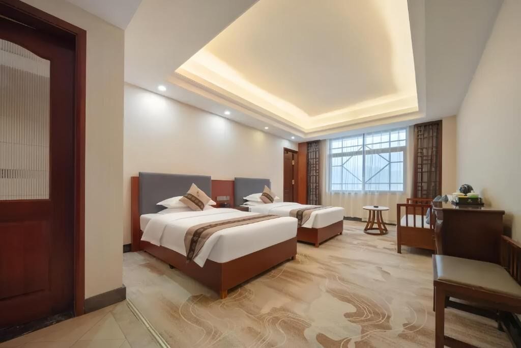 A hotel room with two beds, a desk, and a chair.